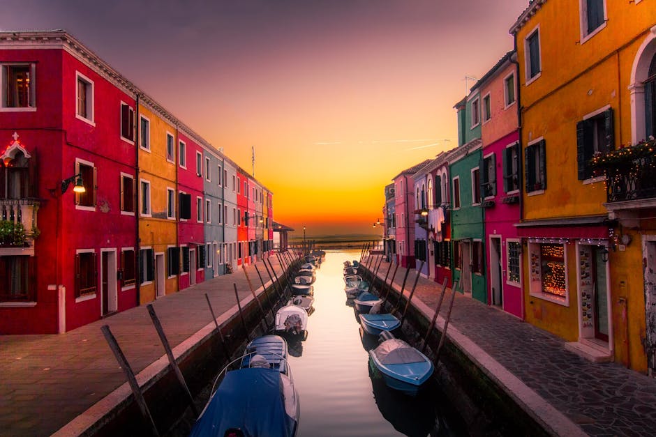 Vibrant facades along Burano's canal with boats at serene sunset. Perfect travel snapshot